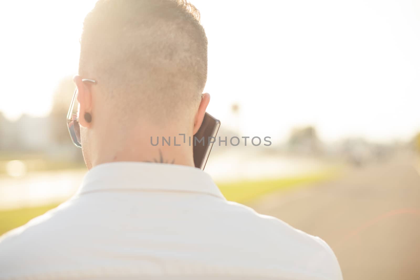 Man with mobile phone in hands, back view, outdoor by adamr