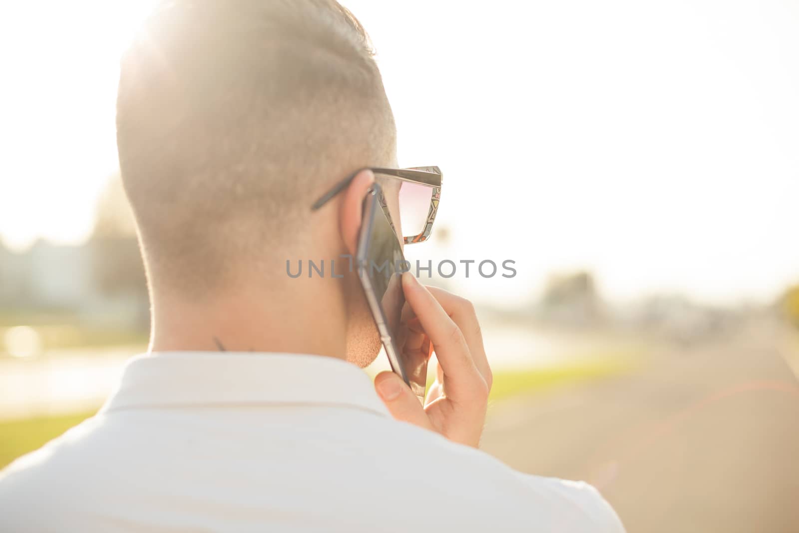 Man with mobile phone in hands, back view, outdoor by adamr