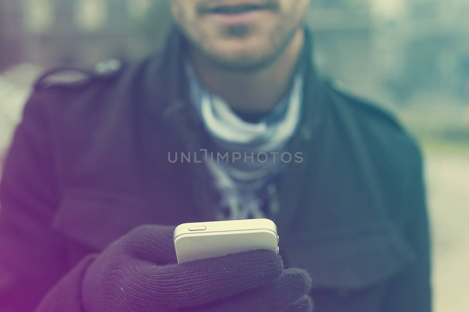Mobile phone in hands with glowes, cold weather by adamr