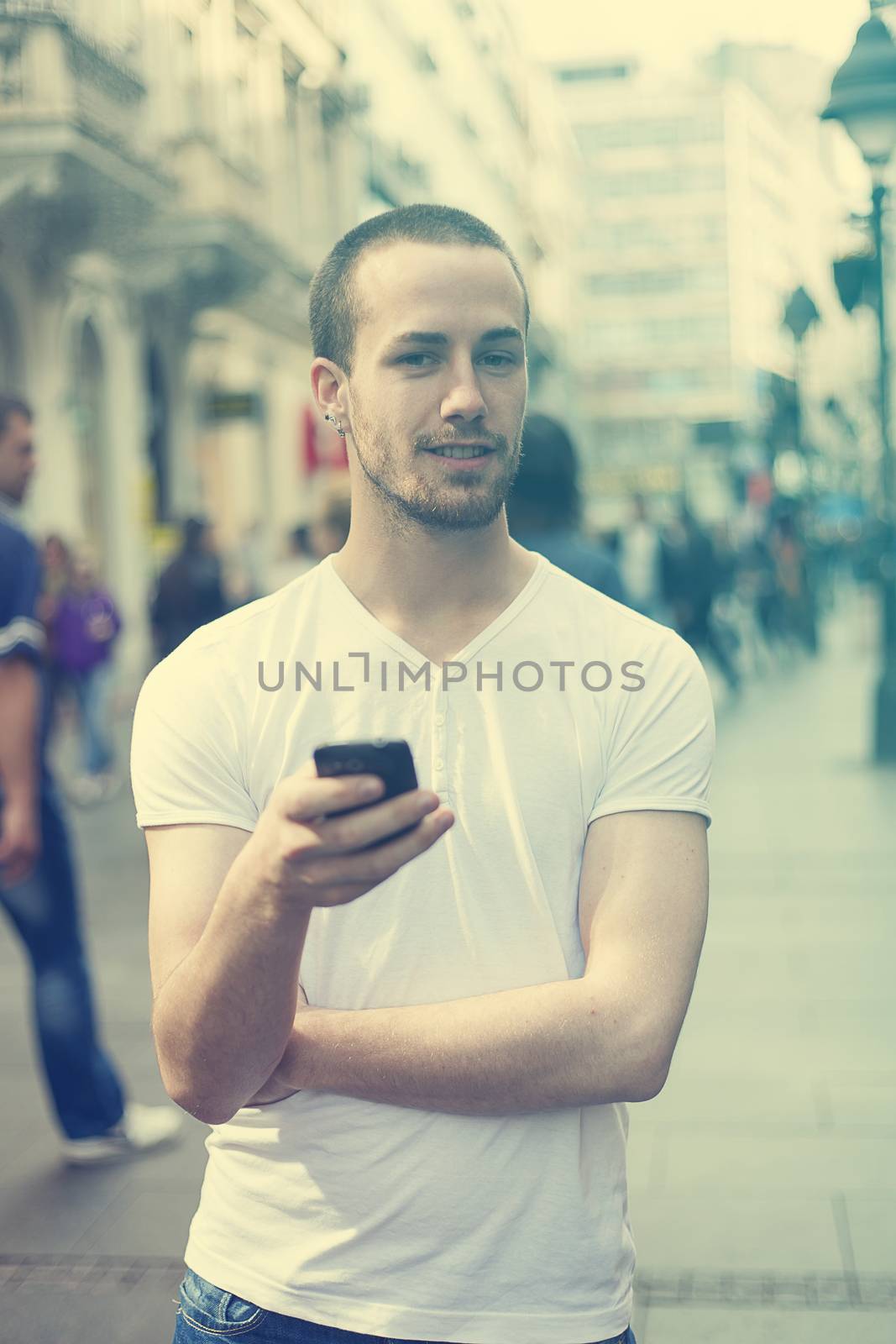 Young Man with mobile phone walking, background is blured city