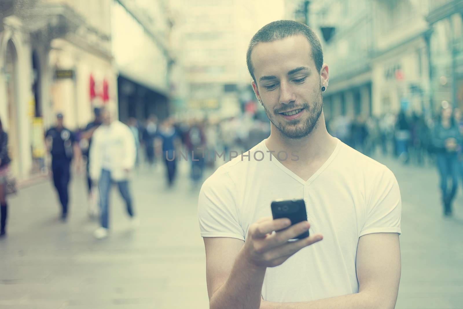 Young Man with mobile phone walking, background is blured city