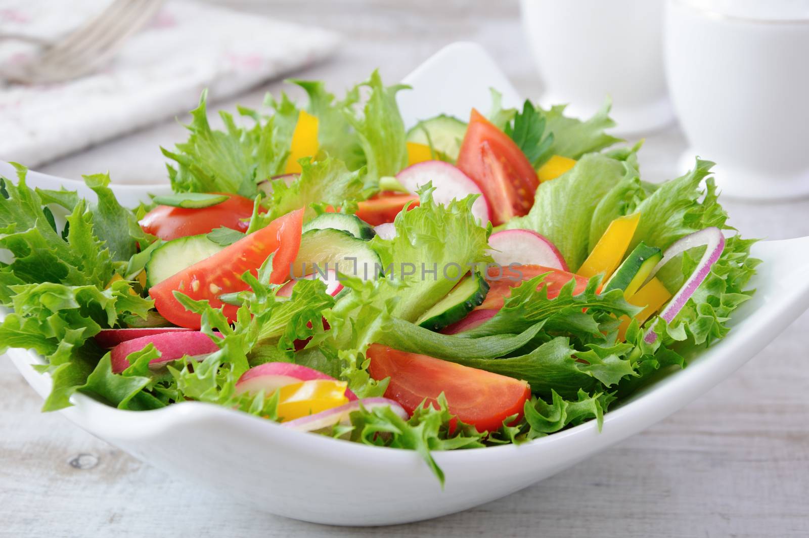 Summer vegetable salad from lettuce leaves with slices of crispy cucumber, tomato slices, radish, seasoned with herbs with fragrant sweet yellow pepper.
A great idea for a healthy lifestyle.
