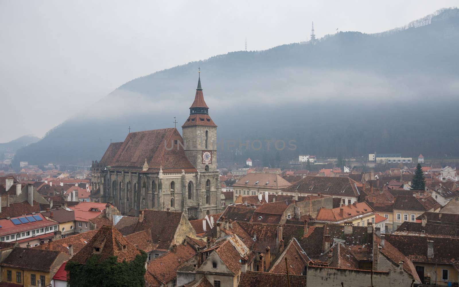 Panoramic  view of Brasov old town and Black Church with the Carpathian Mountains in a foggy winter day. Transylvania, Romania