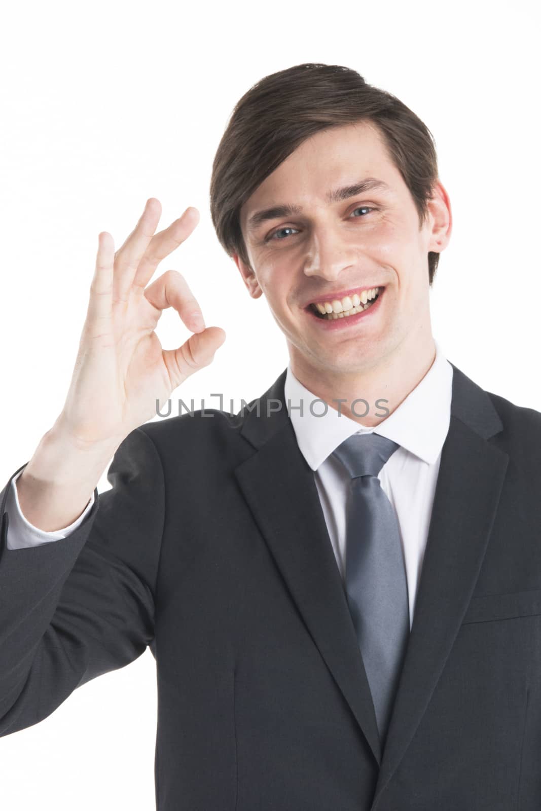 Everything is OK! Happy young business man in suit and tie gesturing OK sign and smiling standing isolated on white background
