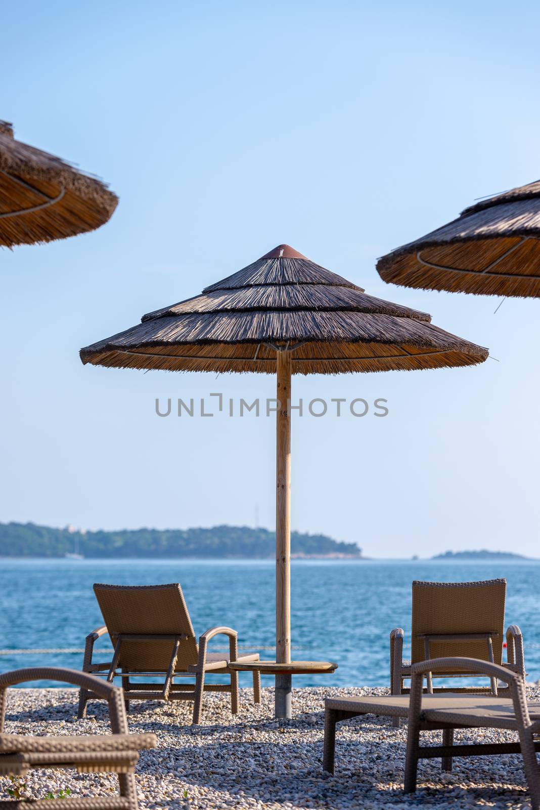 Reed umbrellas and rattan deck chairs on the beach