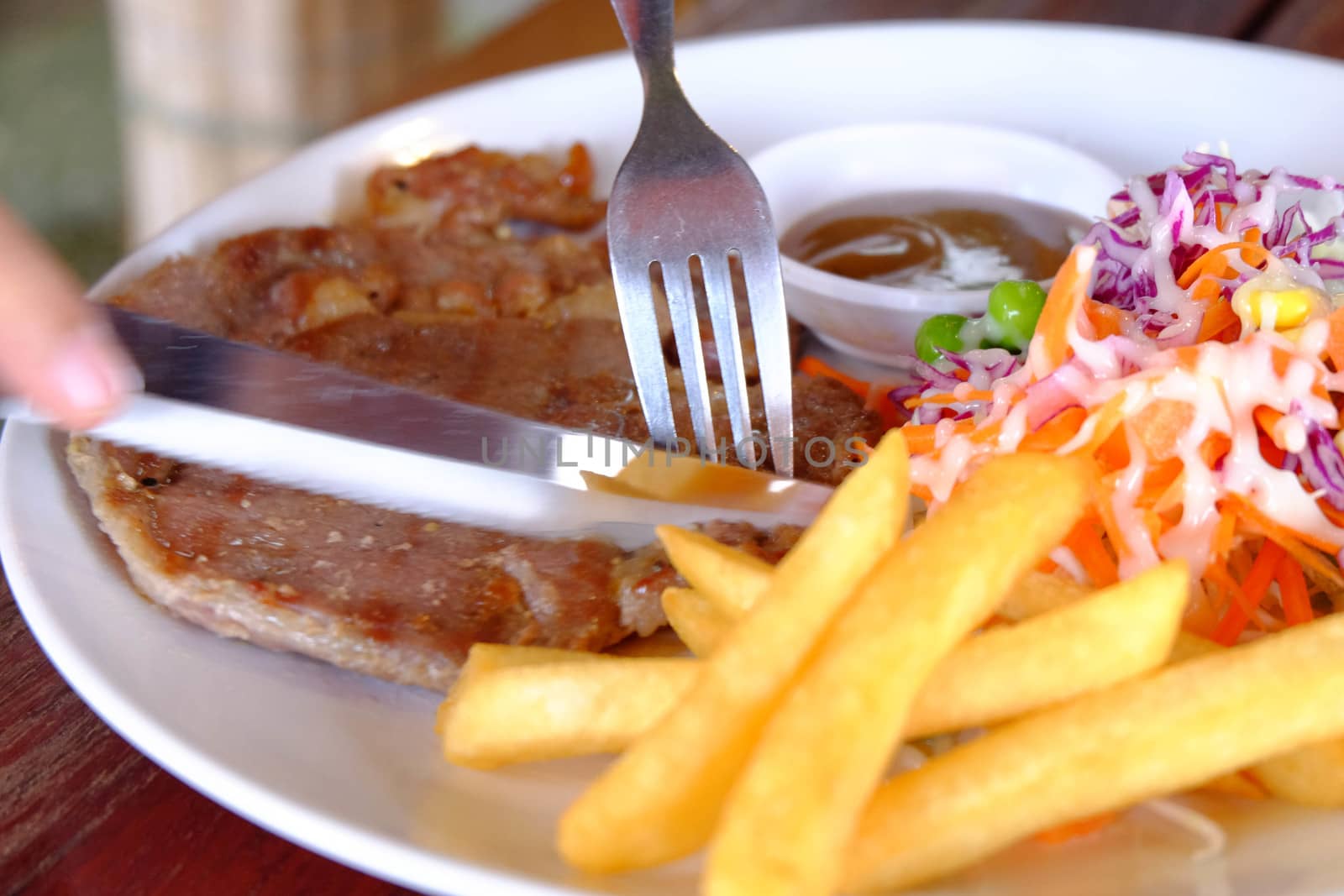 Close up of a cutting a fillet steak with french fries and veget by e22xua