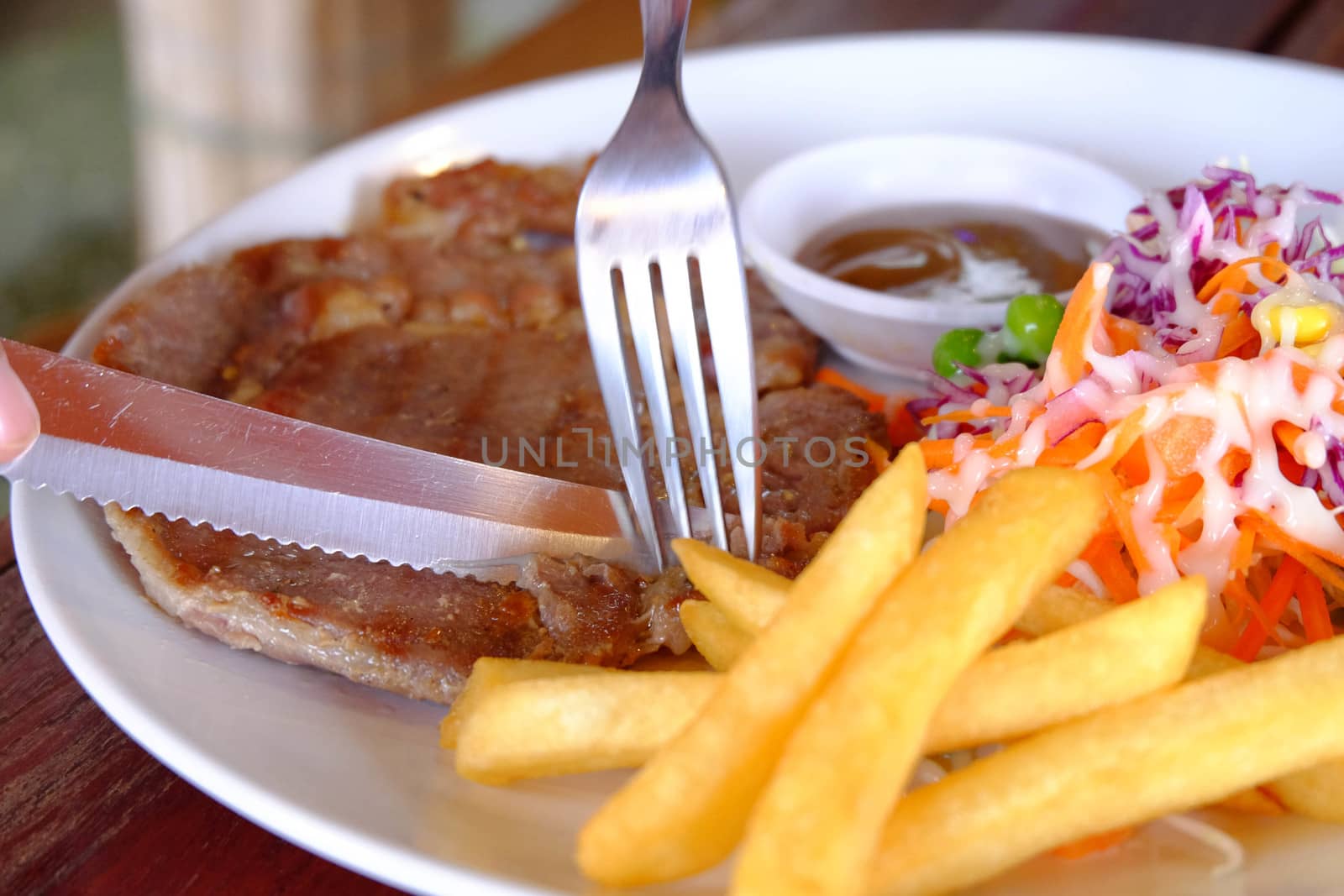 Close up of a cutting a fillet steak with french fries and veget by e22xua