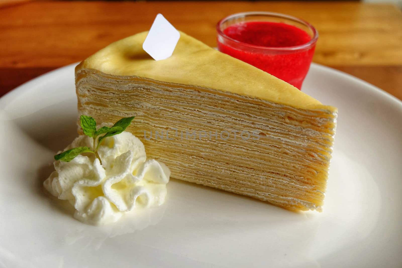 Crepe cake with cream and strawberry and sauce in ceramic cup on by e22xua
