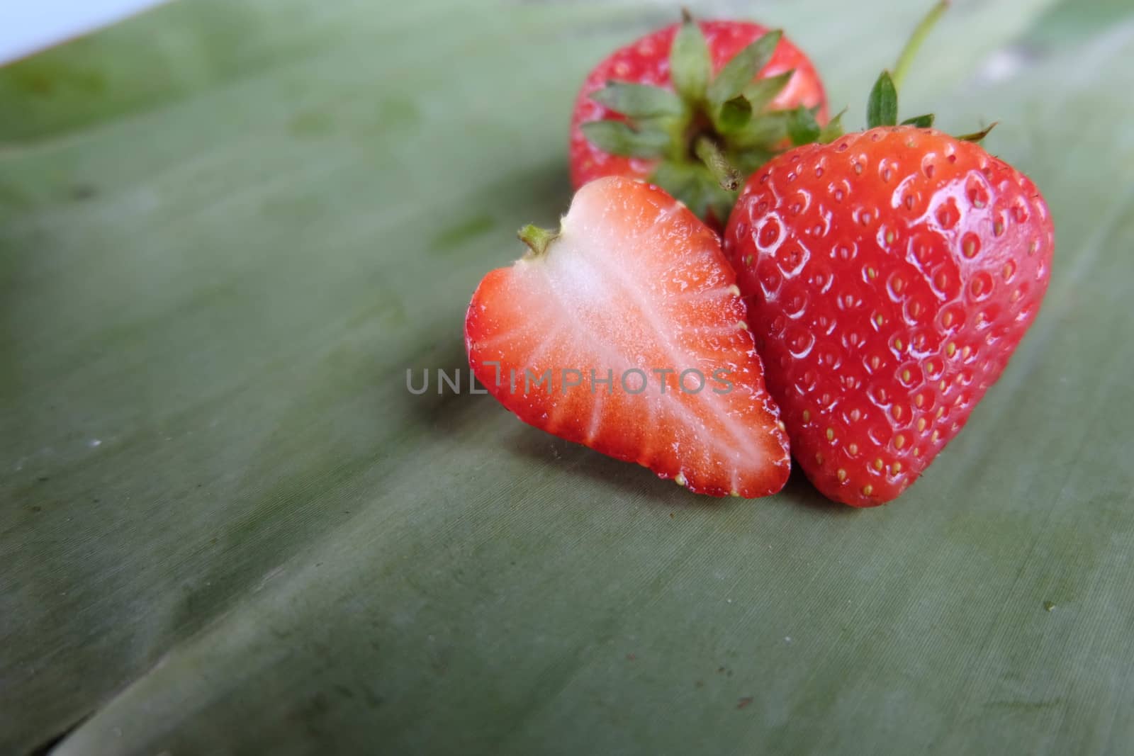 Red strawberry sliced on banana leaf by e22xua