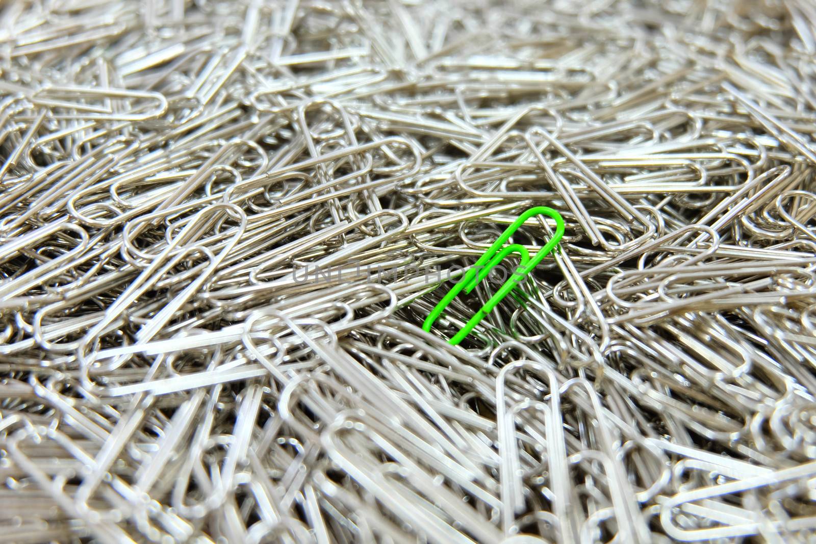 Green paper clip on paper clips background. by e22xua