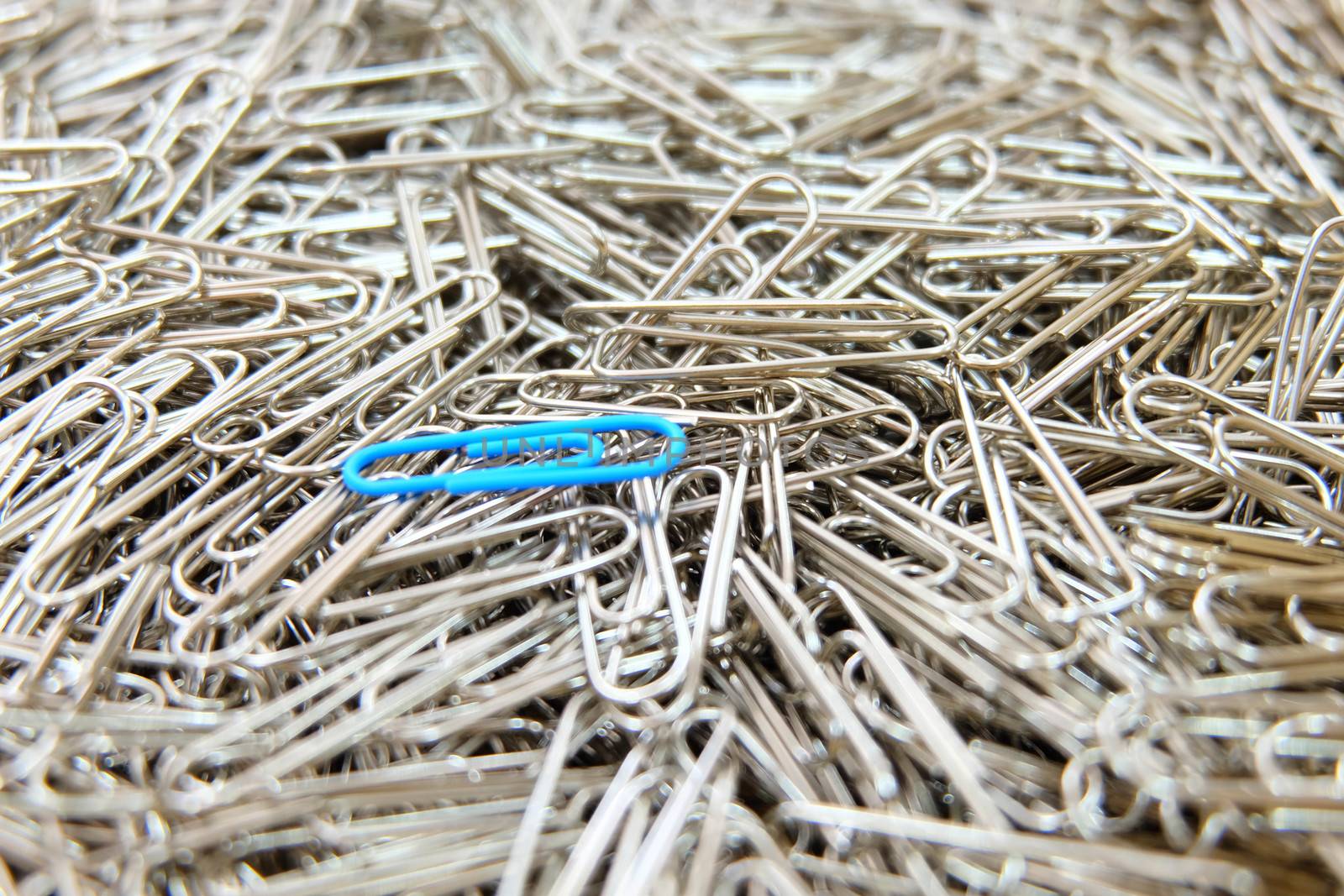 Blue paper clip on paper clips background. by e22xua