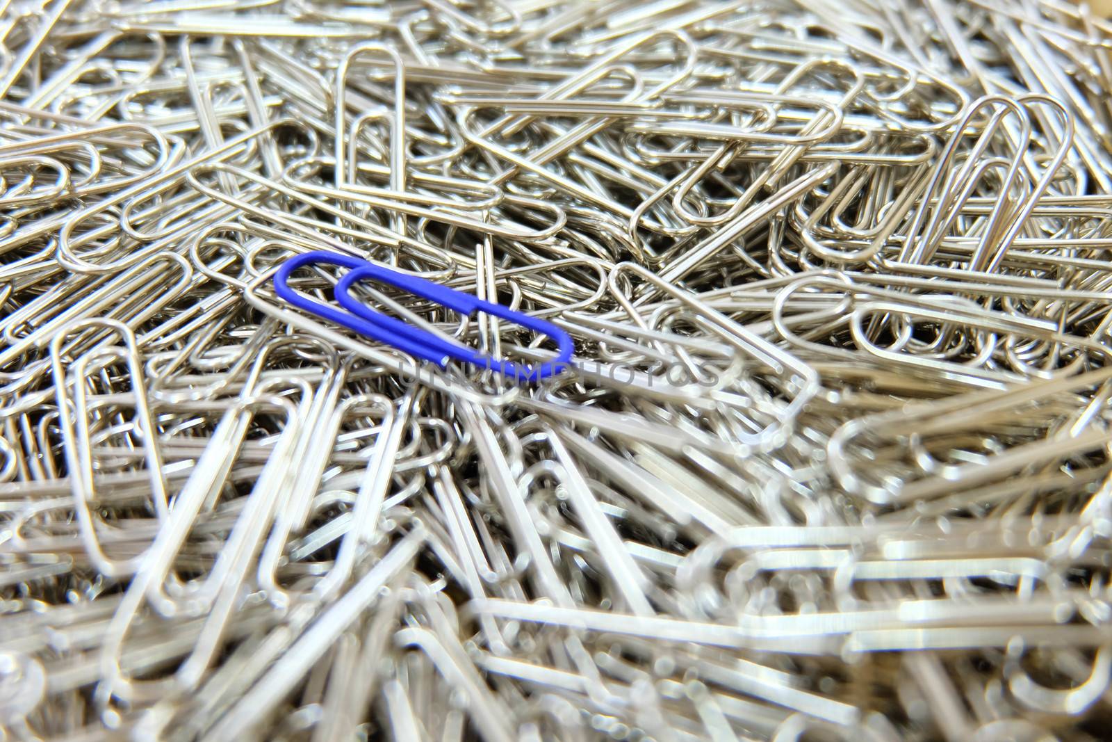Dark blue paper clip on paper clips background. by e22xua