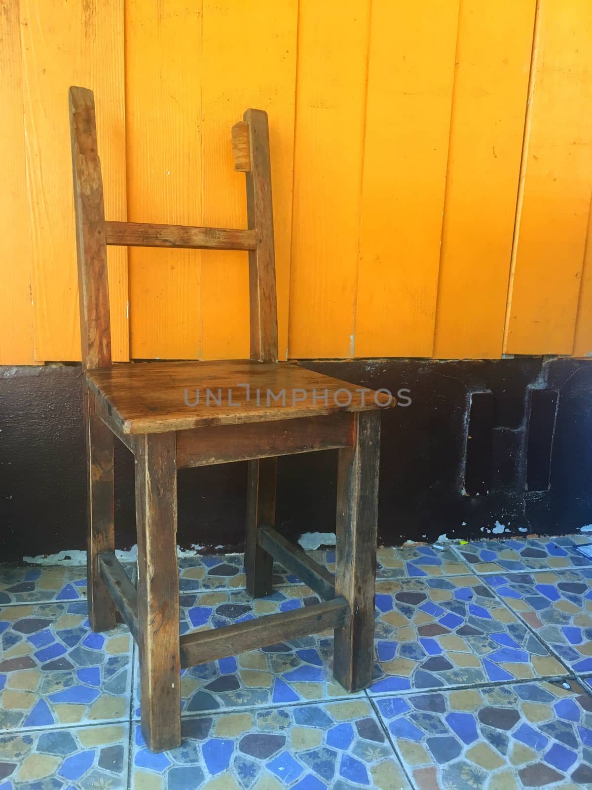 Broken wooden chair and orange painted wooden backdrop