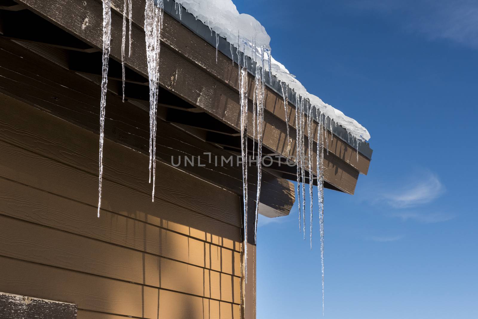 Icicles hanging from a building during winter by Njean