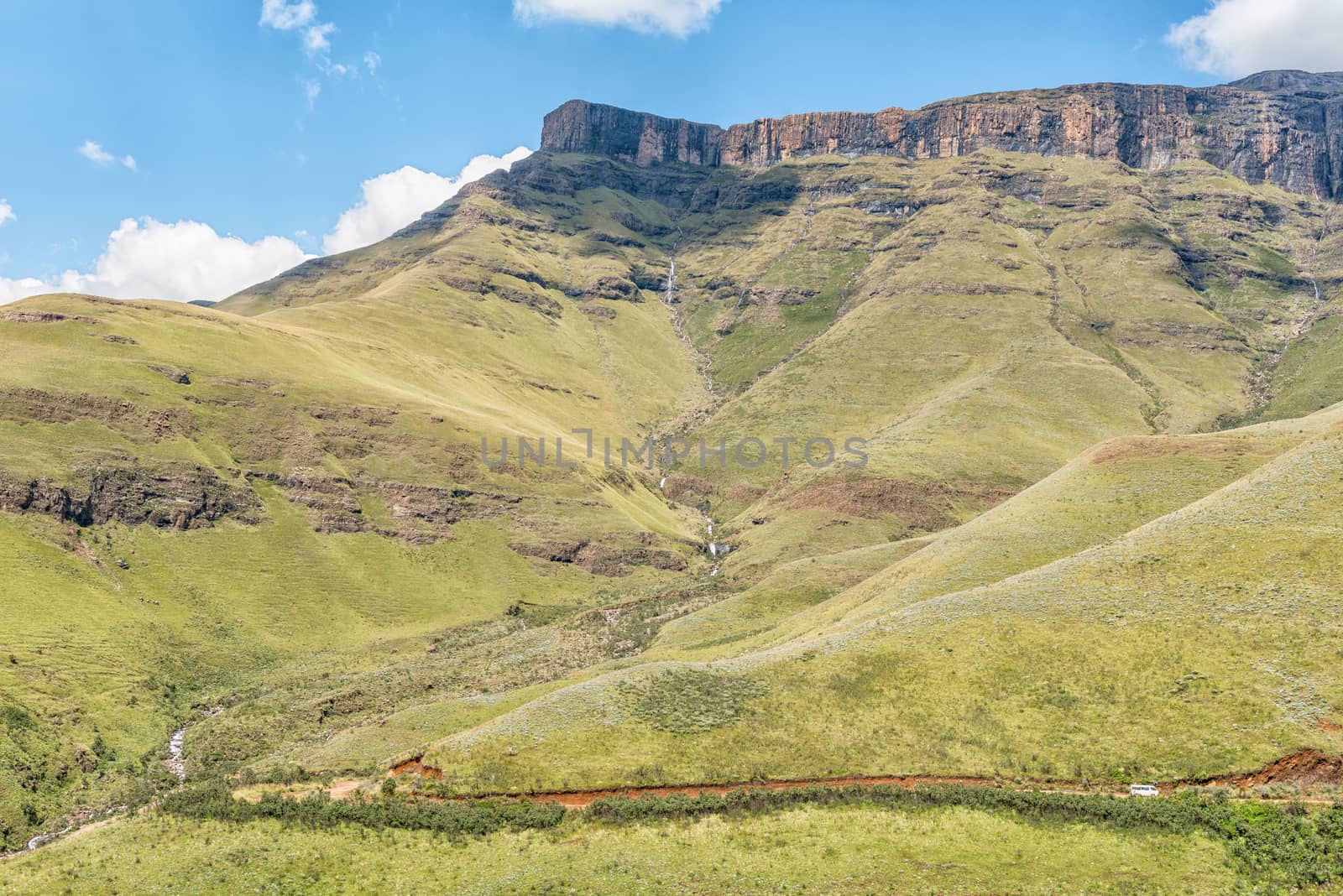 A waterfall next to the Sani Pass near Himeville, in the Kwazulu-Natal Province of South Africa. A minibus is visible on the pass