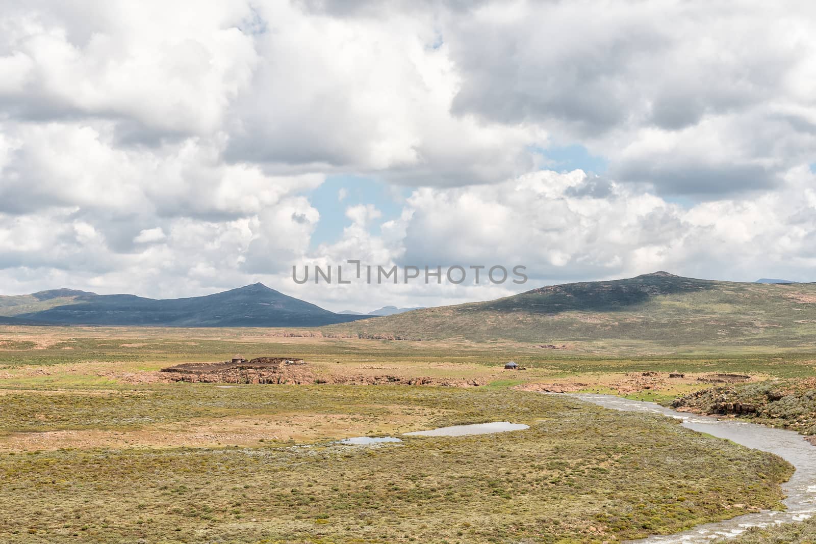 A farm landscape at the foot of the Black Mountain Pass. A river, stone huts and sheep are visible