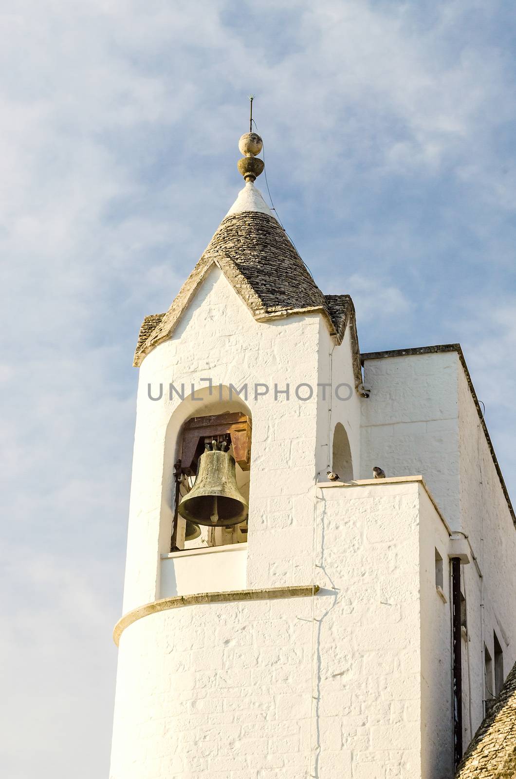 Belltower of the Trullo church in Alberobello, Italy. Trulli buildings are typical iconic houses in Apulia region