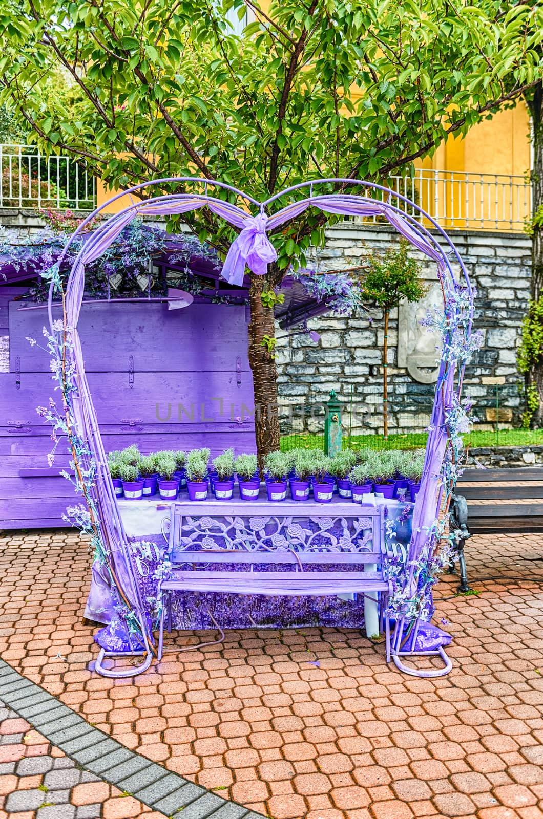 Scenic heart-shaped violet bench decorated with flowers and laces. Love concept