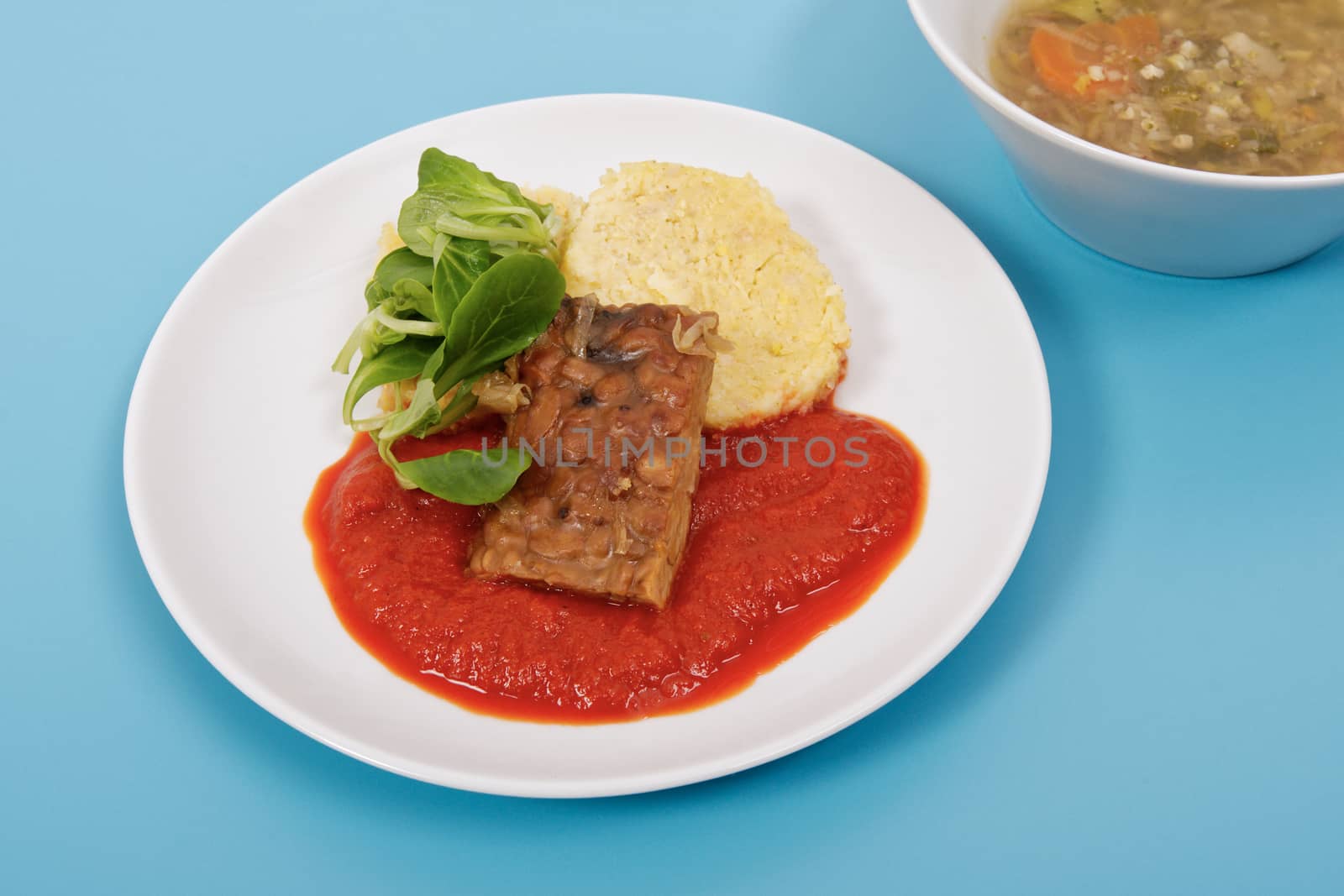 Tempeh with tomato sauce and dumplings on a blue background