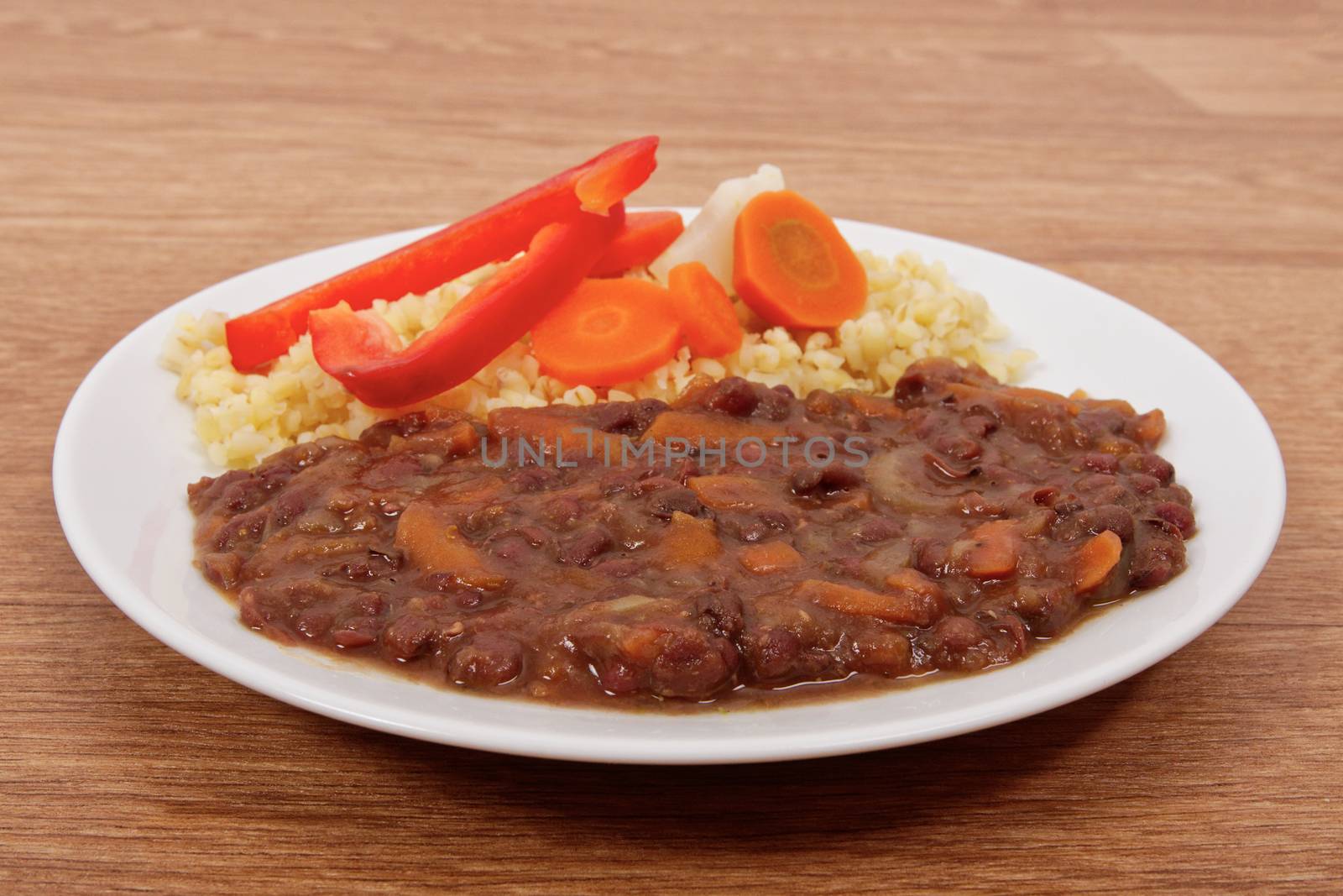 Azuki with vegetables on steam and bulgur on a wooden table