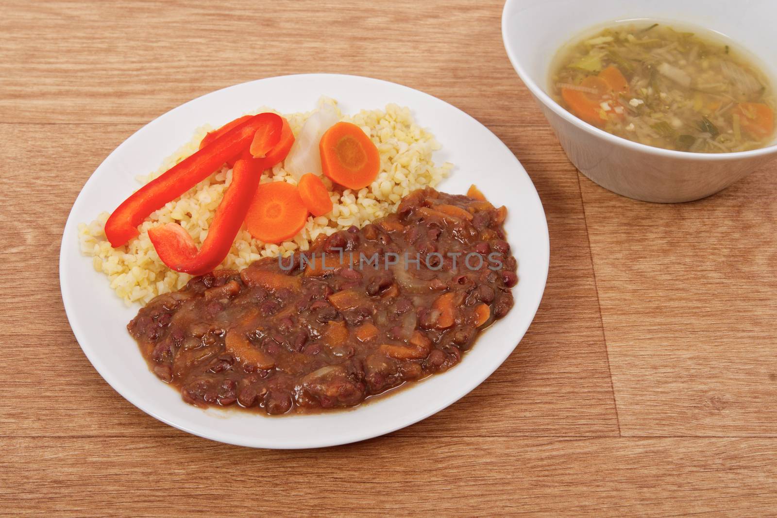 Azuki with vegetables on steam and bulgur on a wooden table