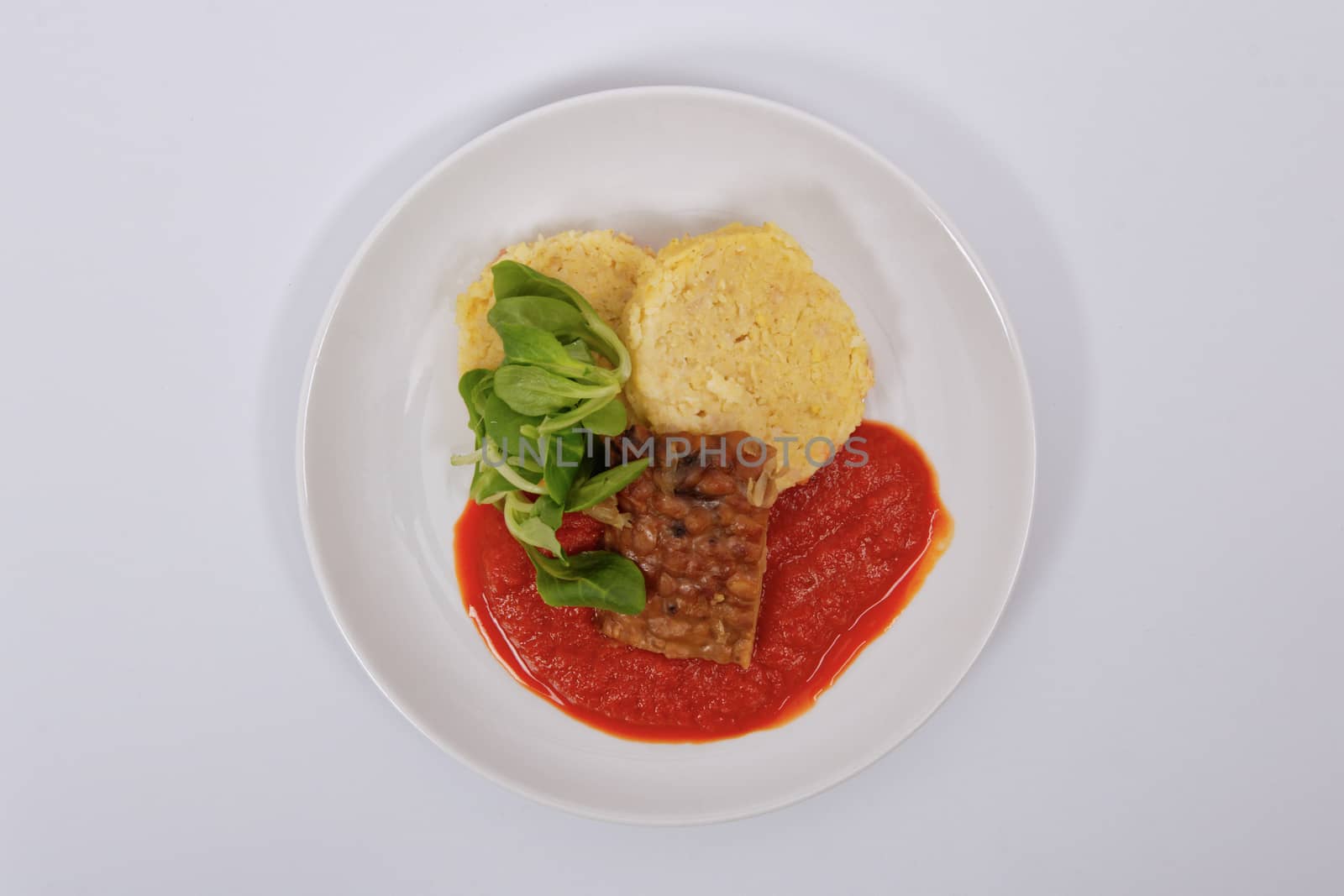 Tempeh with tomato sauce and dumplings on a white background