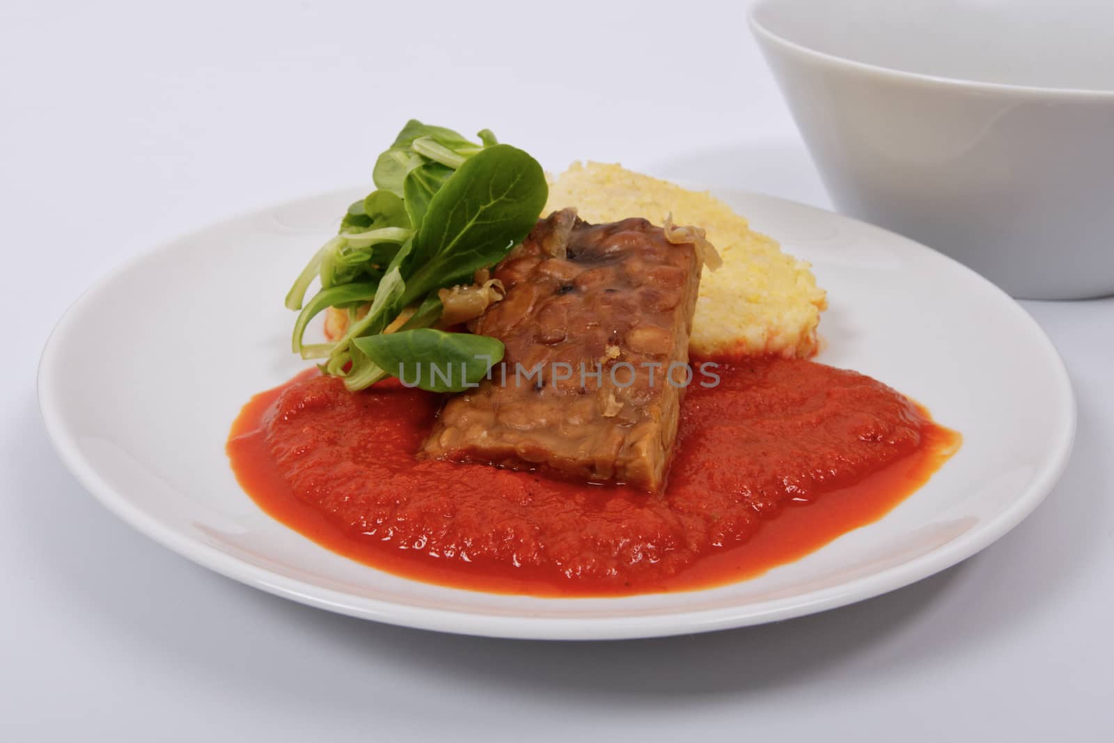 Tempeh with tomato sauce and dumplings on a white background