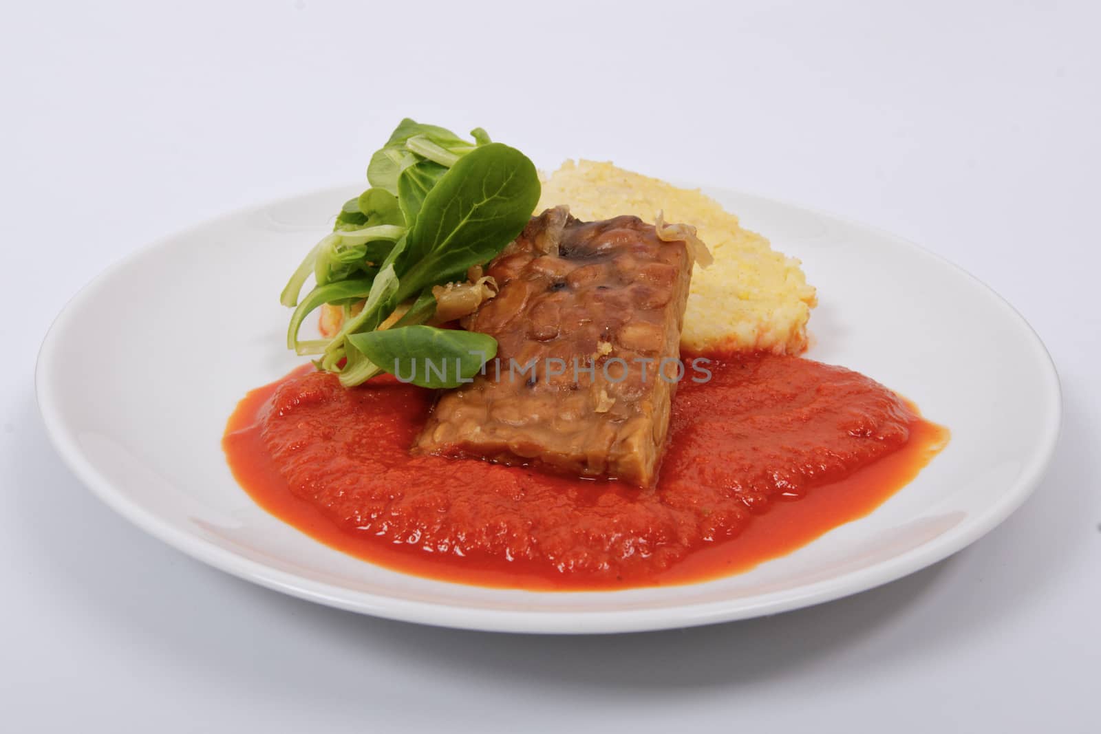 Tempeh with tomato sauce and dumplings on a white background