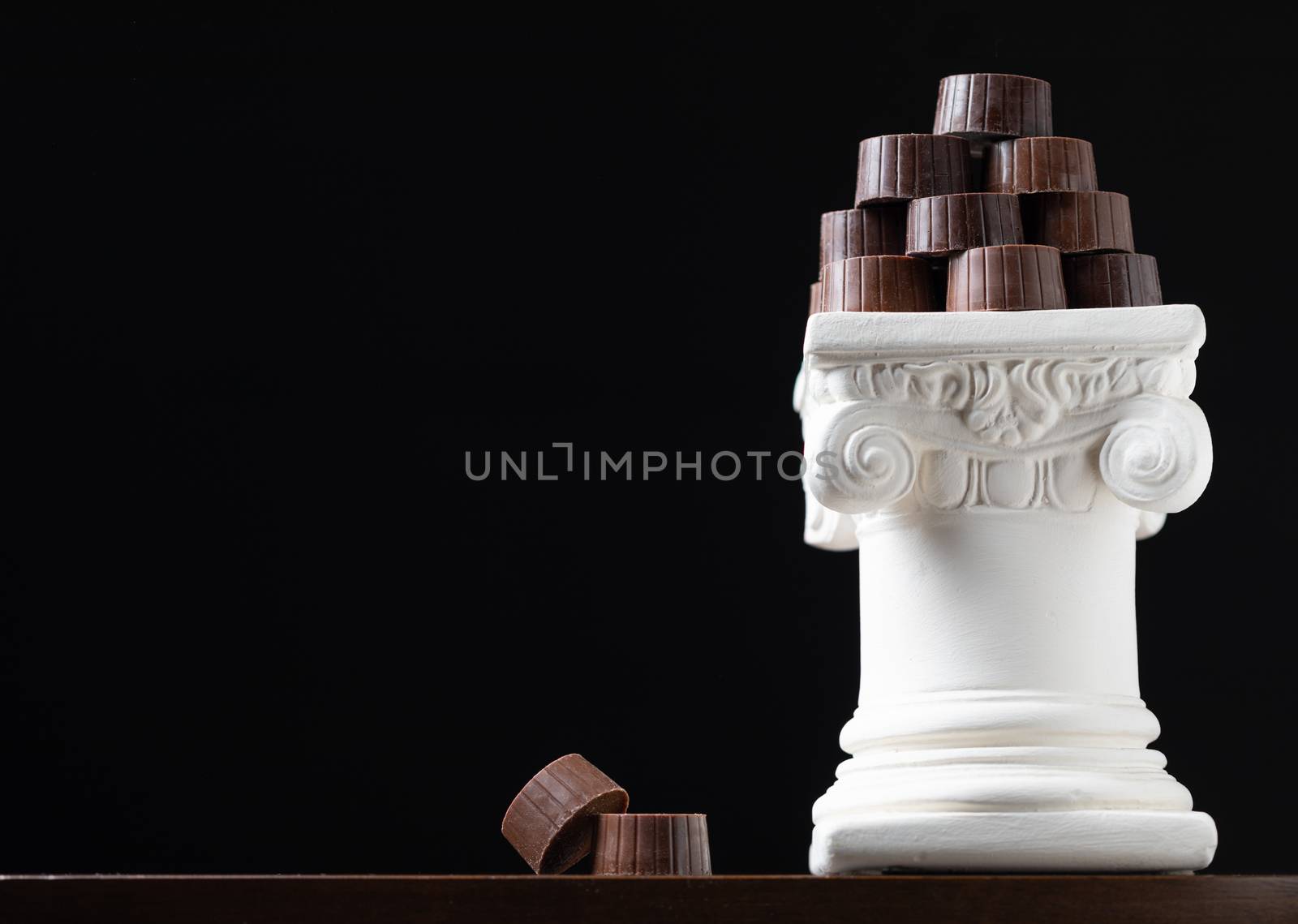 Stack of Fine Artisan Chocolates Stacked On White Pillar Column by Feverpitched