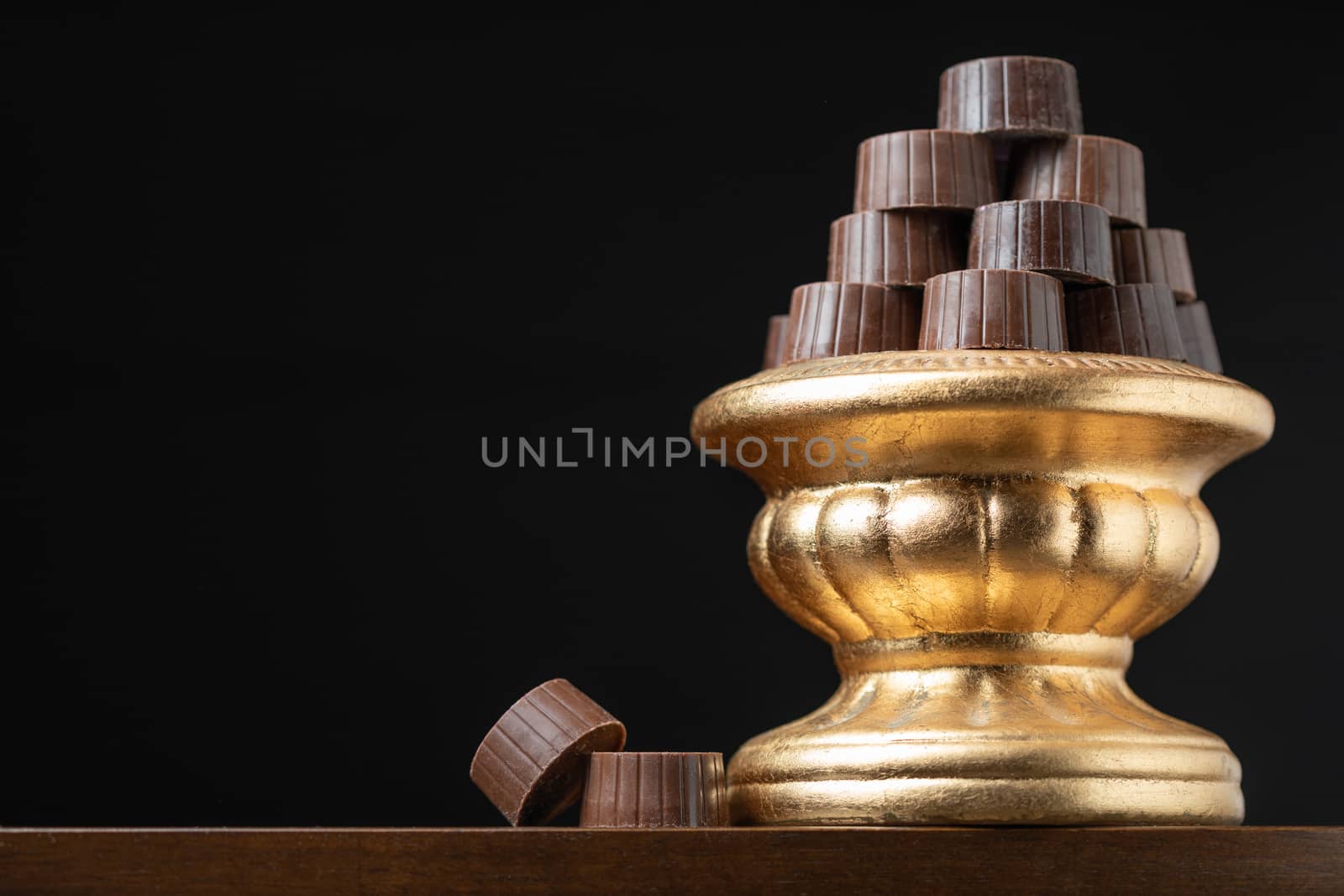 Stack of Fine Chocolates On Golden Pillar Dish With Dark Backgro by Feverpitched