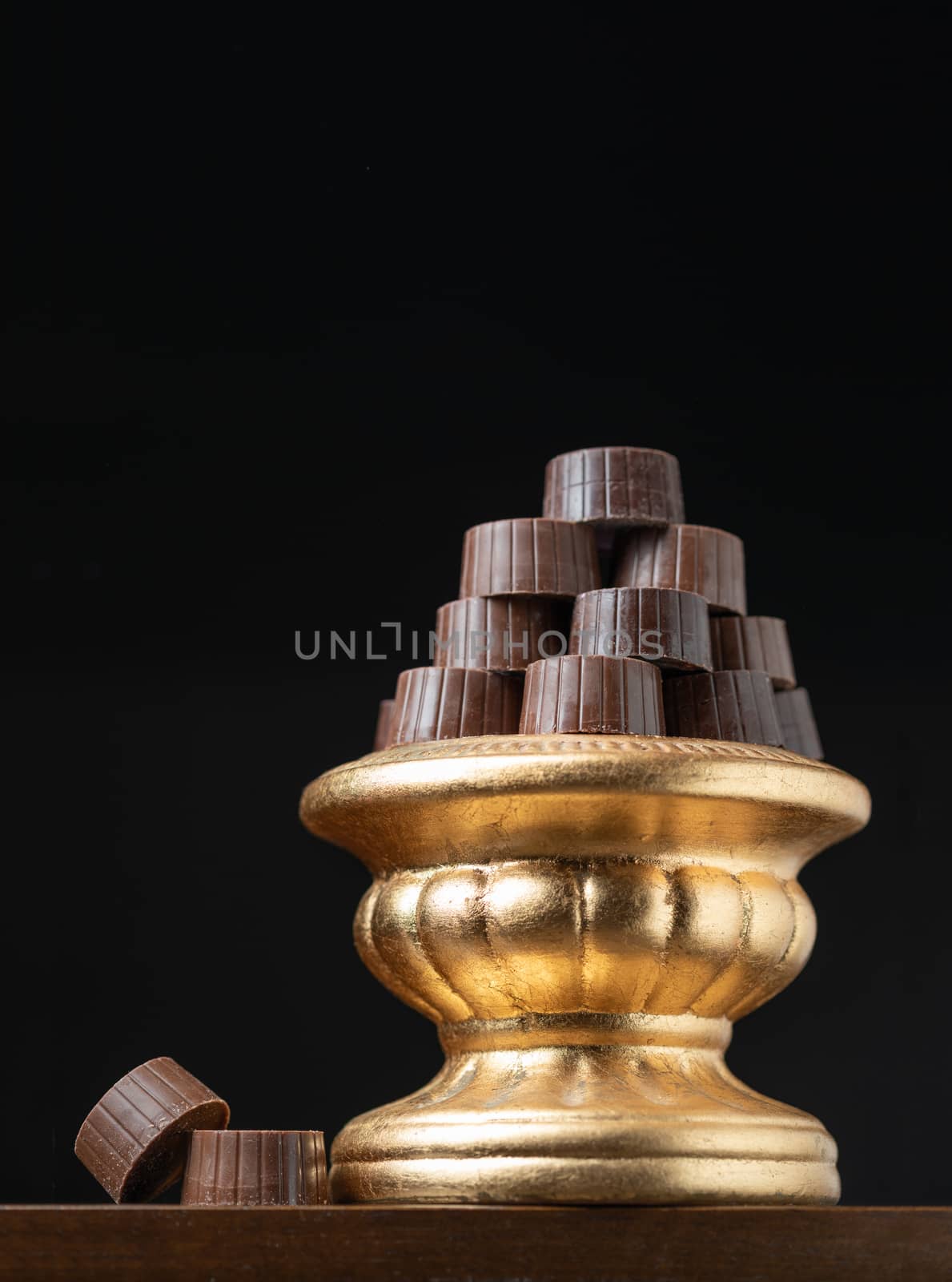 Stack of Fine Chocolates On Golden Pillar Dish With Dark Backgro by Feverpitched