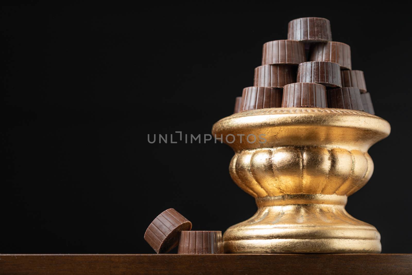 Stack of Fine Chocolates On Golden Pillar Dish With Dark Background.