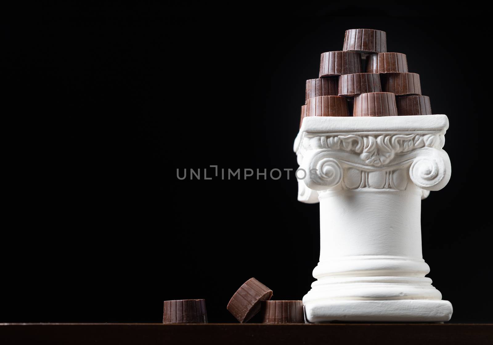 Stack of Fine Artisan Chocolates Stacked On White Pillar Column.