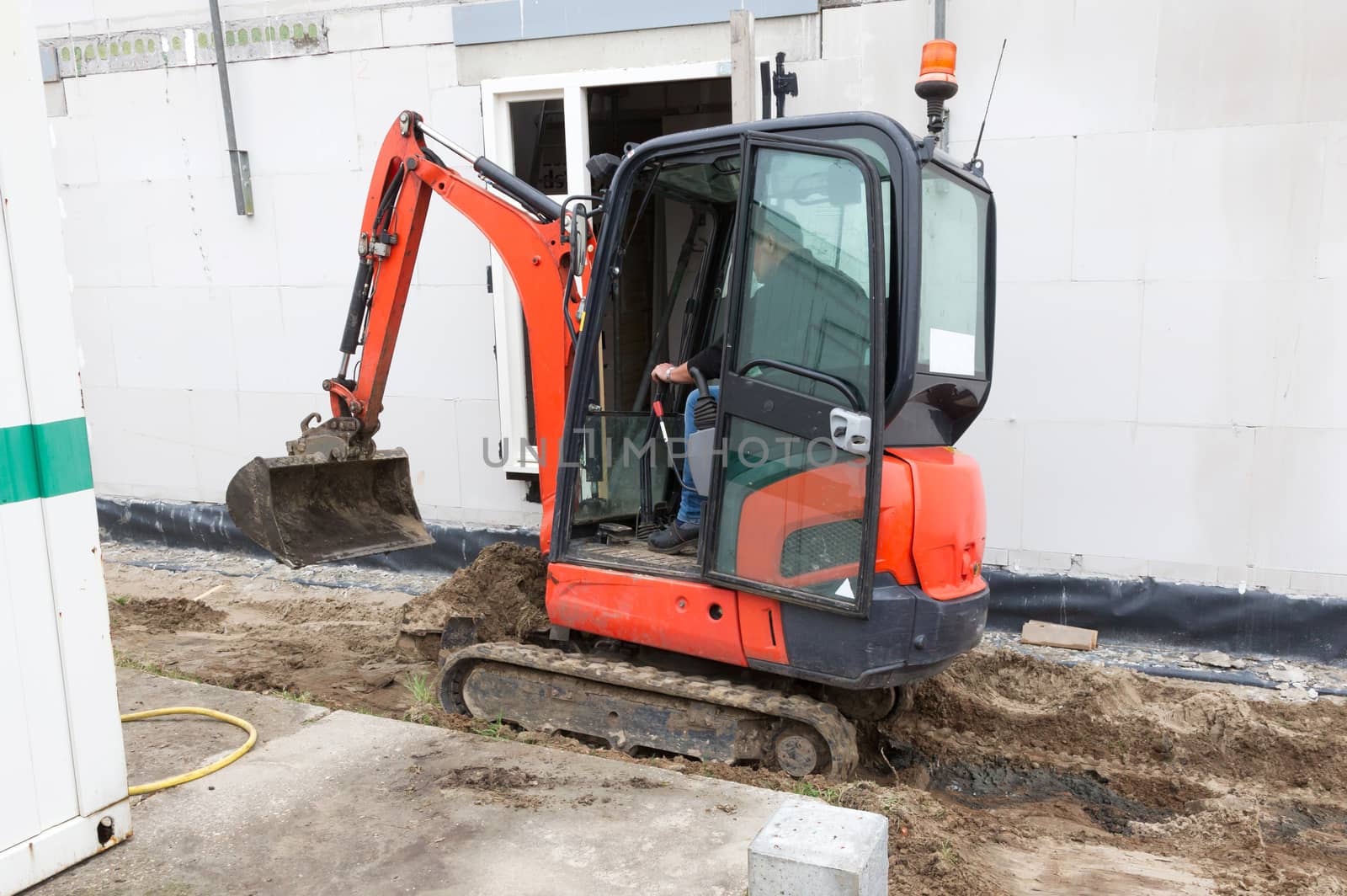 Small crane is leveling ground at a building site of a dutch house