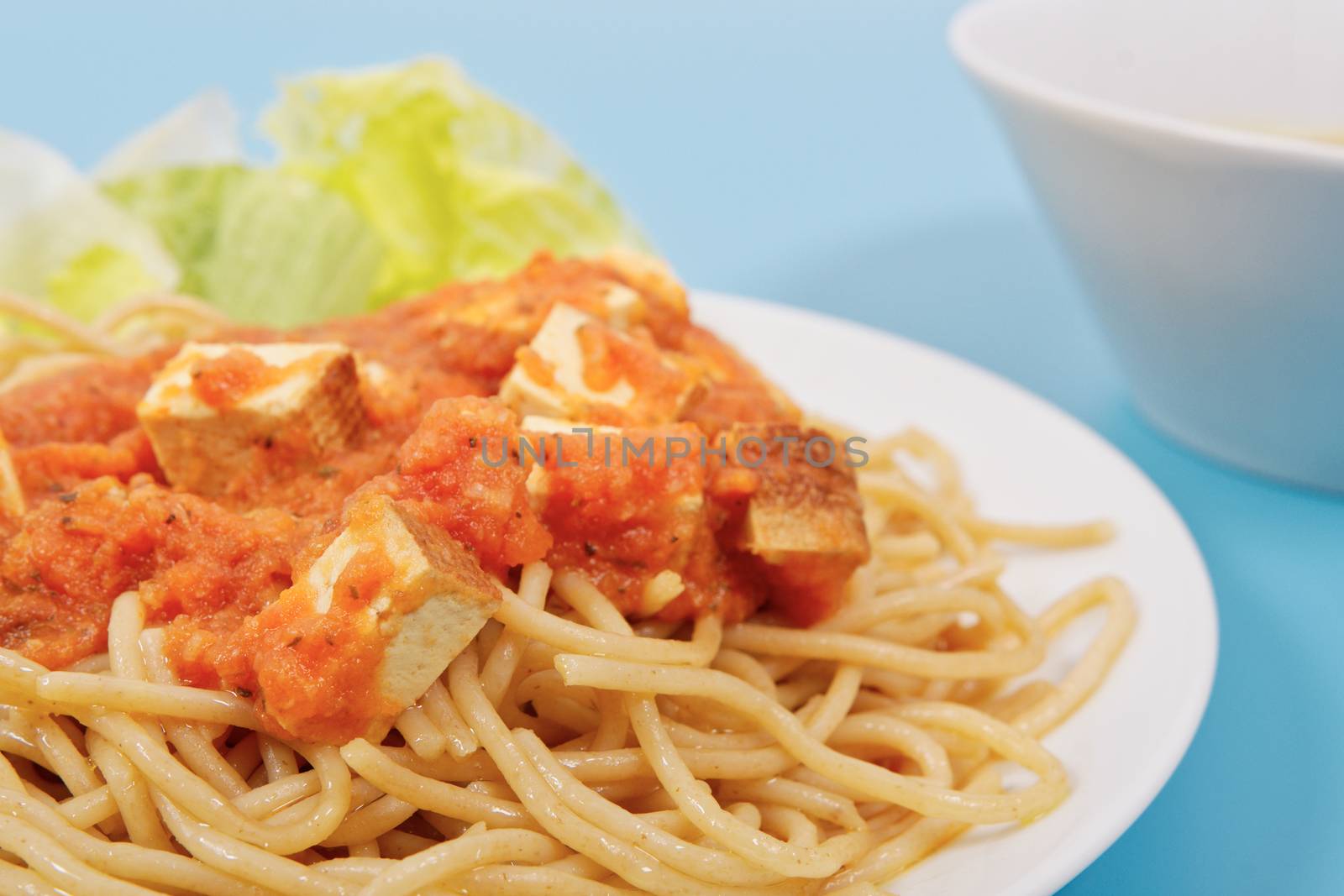 Bolognese spaghetti with tofu on a blue background