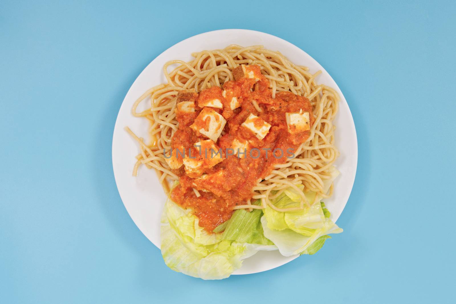 Bolognese spaghetti with tofu on a blue background