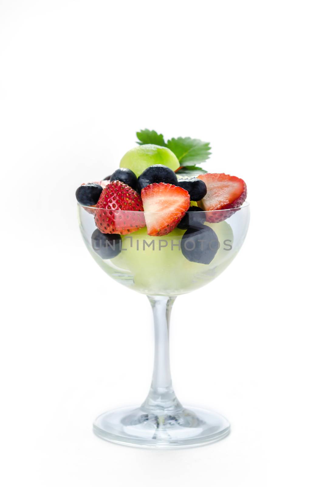 Fresh forest berries and melon in a glass on a white background