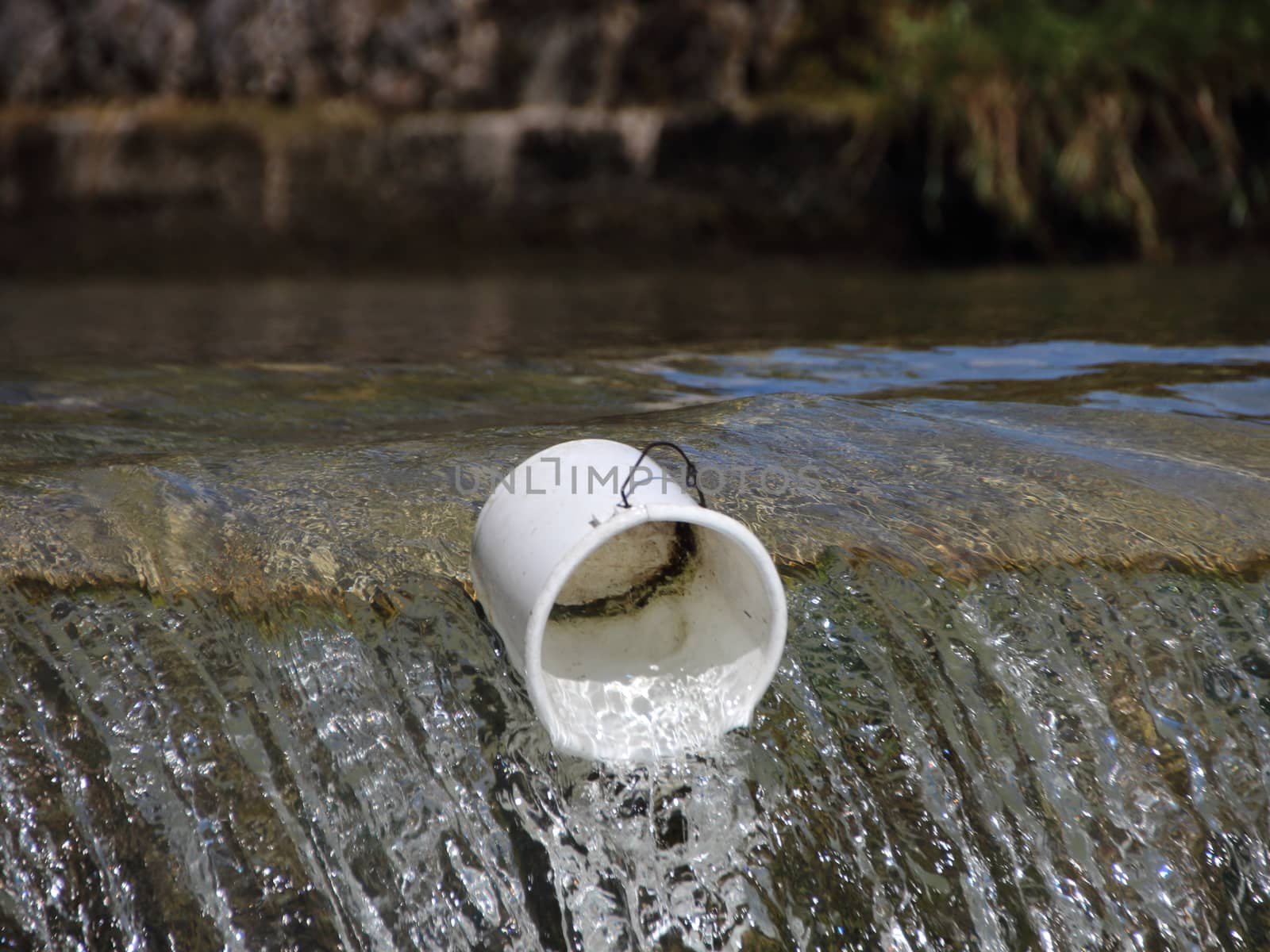 Bucket in Drain Canal with Melting Water from Mountains by HoleInTheBox