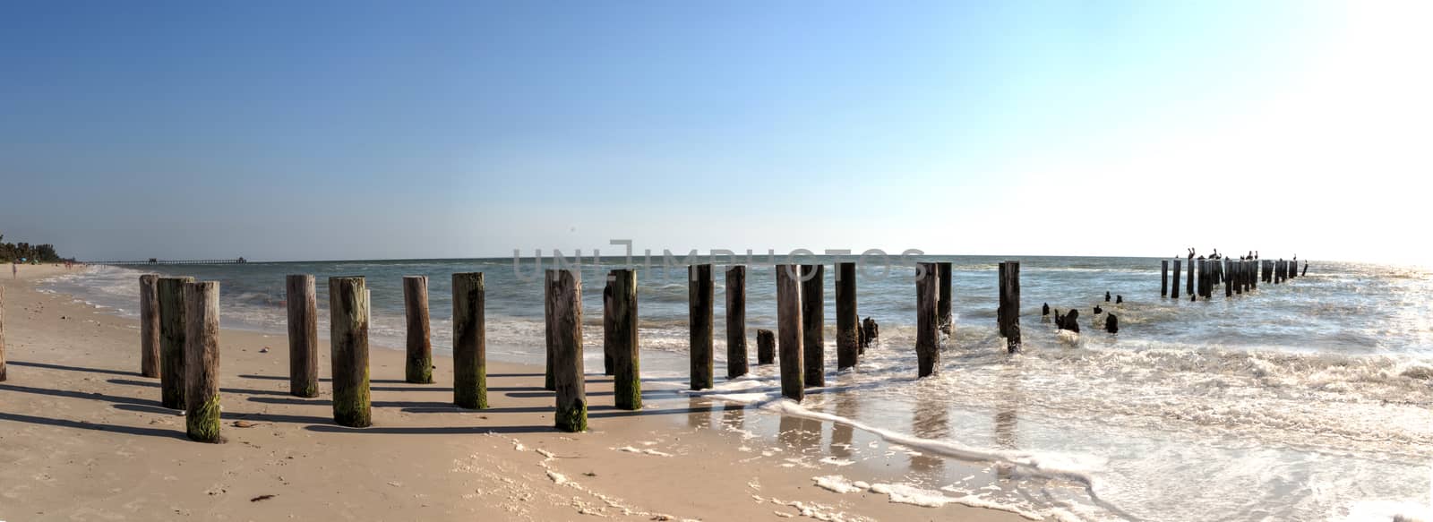 Clear blue sky over the old dilapidated pier on the beach in Naples, Florida