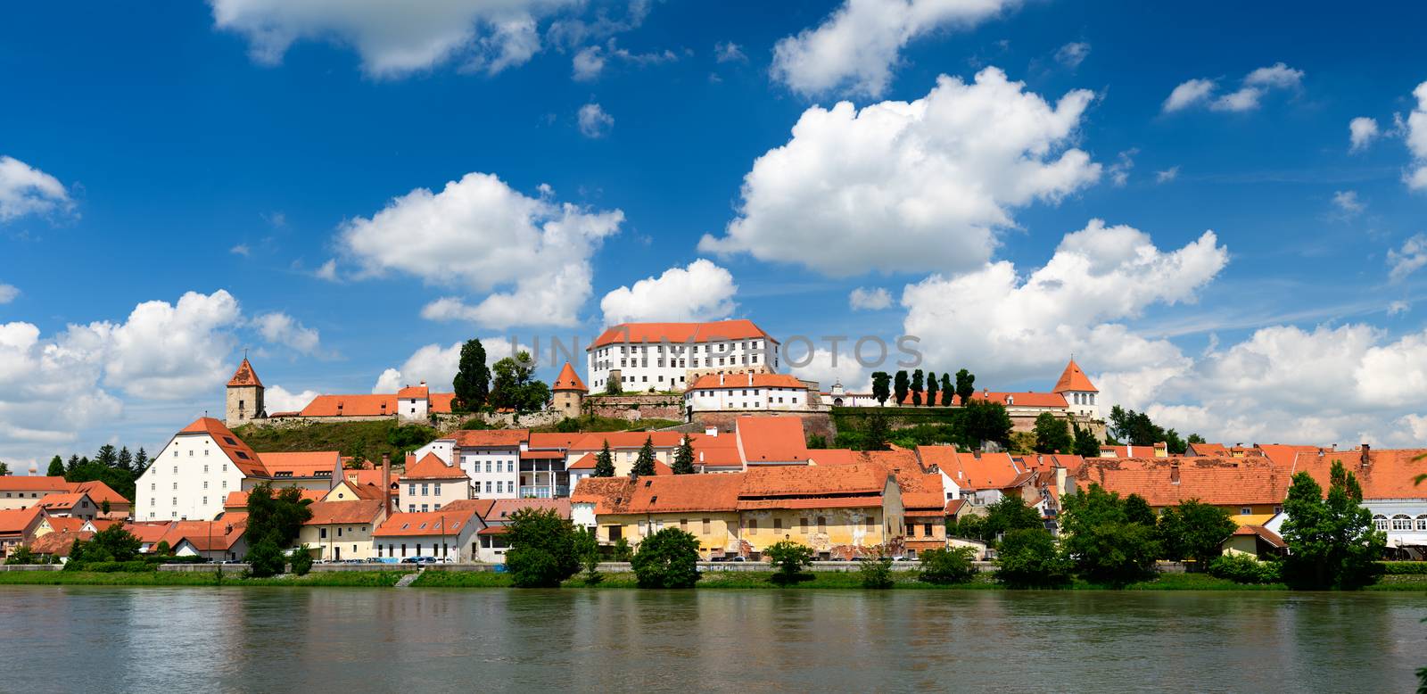 Ptuj, Slovenia, panoramic shot of oldest city in Slovenia with a castle overlooking the old town from a hill and the Drava river beneath, clouds moving across the sky time lapse