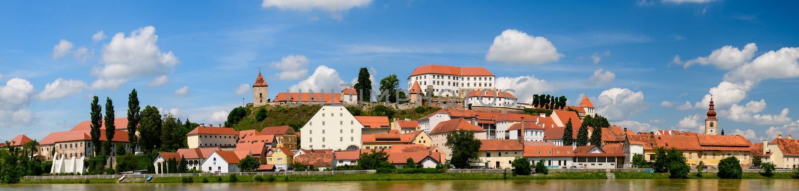 Ptuj, Slovenia, panoramic shot of oldest city in Slovenia with a castle overlooking the old town from a hill and the Drava river beneath, clouds moving across the sky time lapse