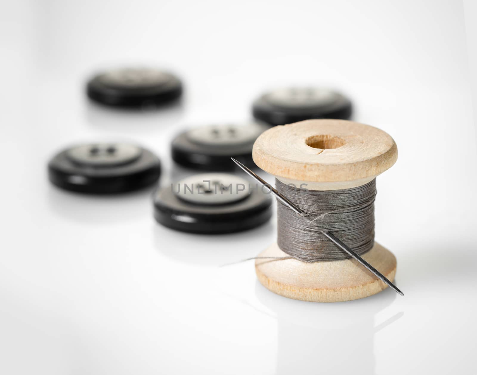 spool of thread and buttons on white background