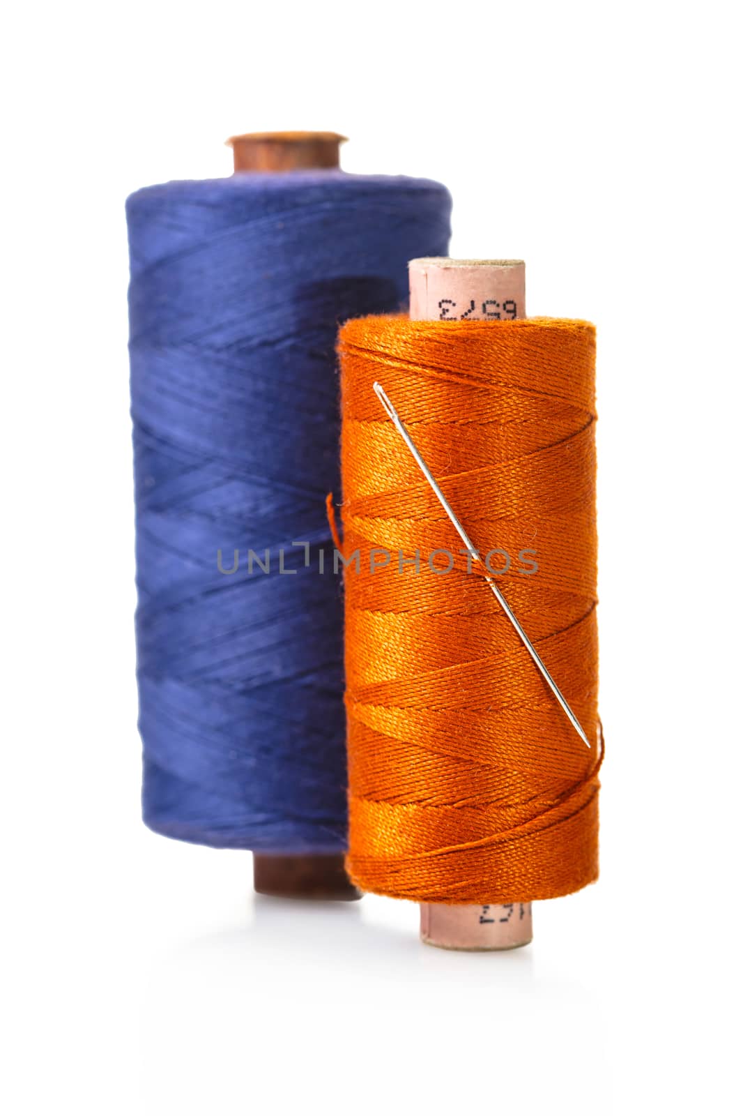 spool of thread with a needle on white isolated background