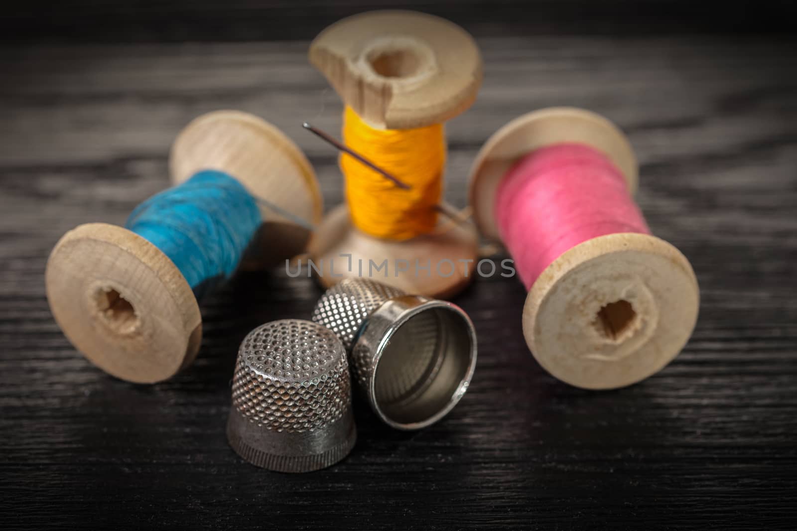 Thread and thimble on a black wooden background
