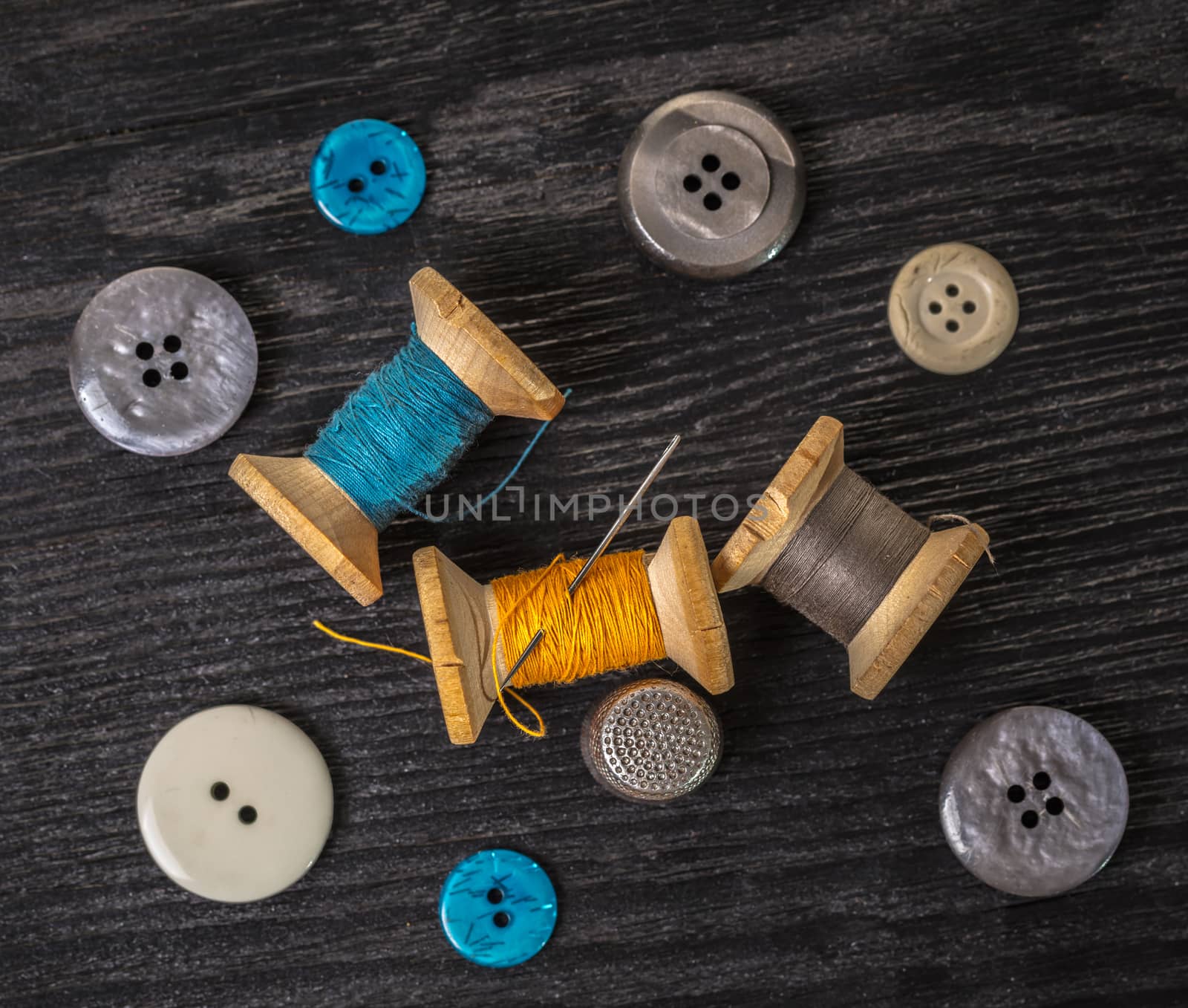 spool of threads and buttons on a wooden background