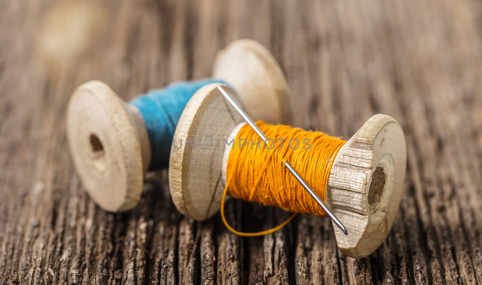 colored threads and needle on wooden background