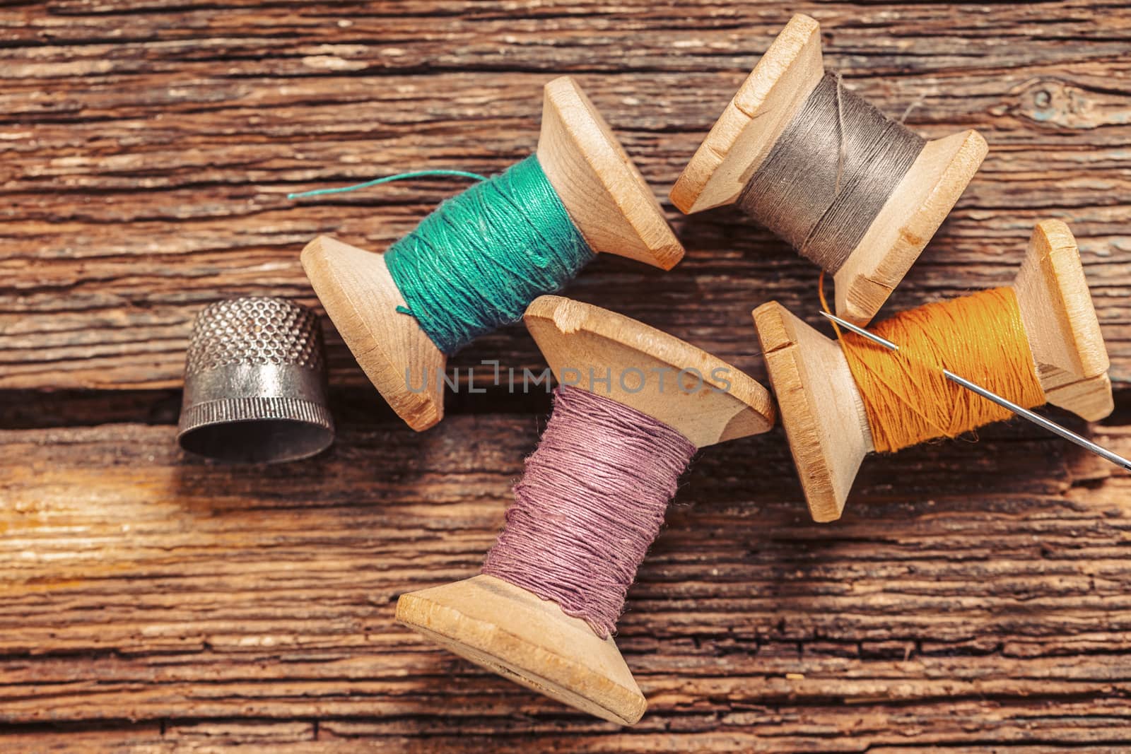 colored threads and thimble on wooden background