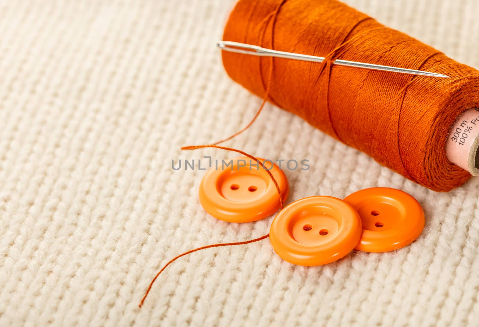 colored thread and buttons on white knitted fabric