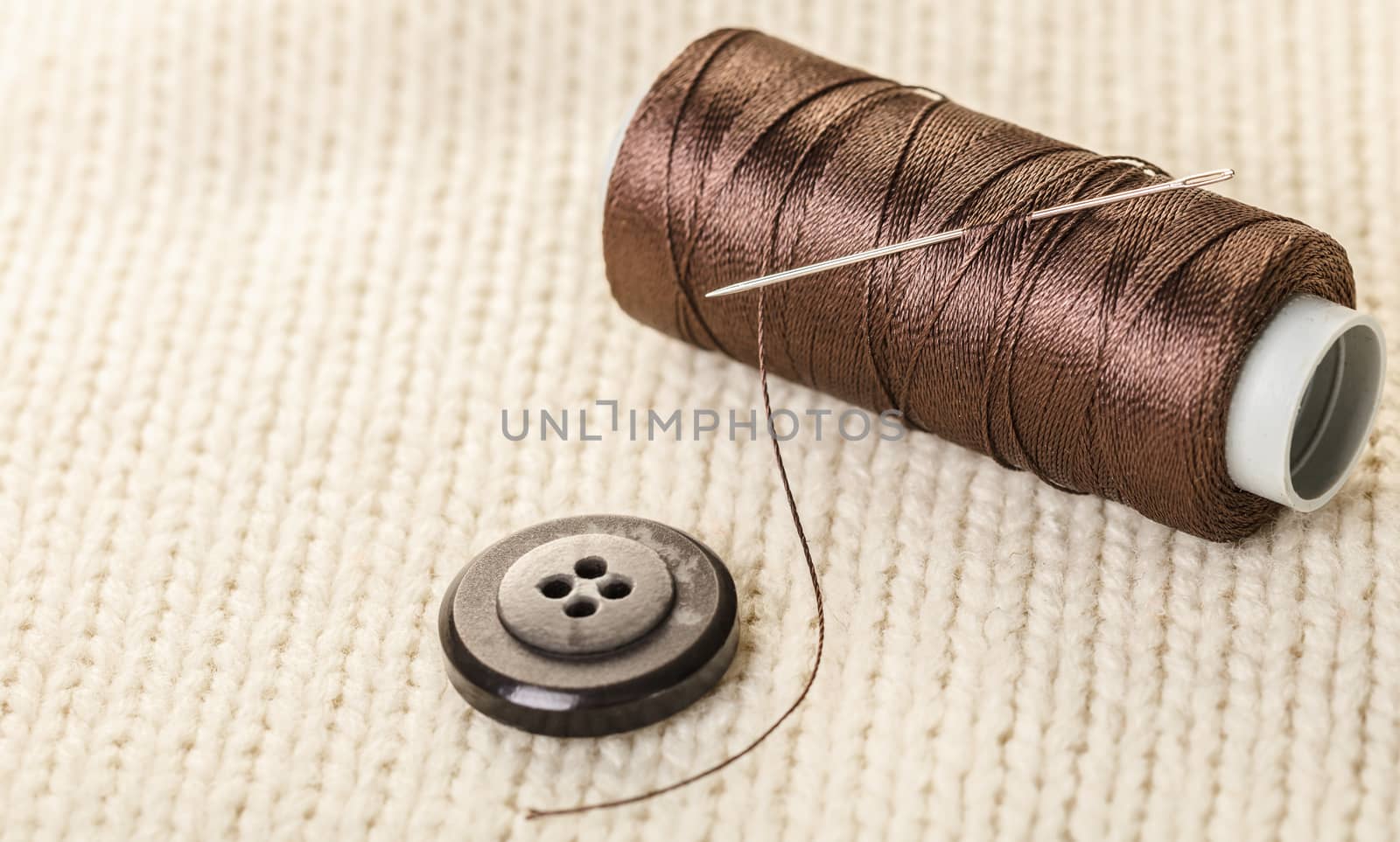 colored thread and buttons on white knitted fabric