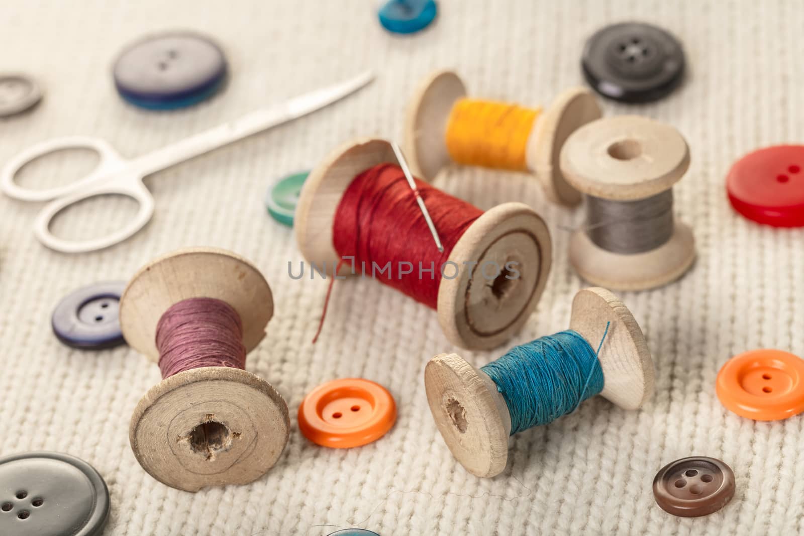 colorful threads and buttons on white knitted fabric